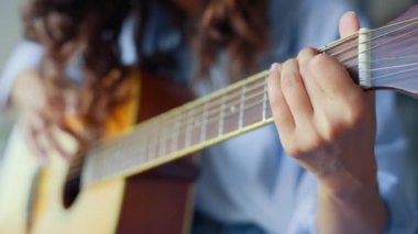 Kadın elleri akustik gitar çalıyor. Genç kız gitarla şarkı yapıyor.