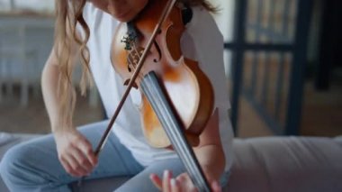 Kız kemanla beste yapıyor. Müzisyen enstrüman üzerinde müzik oluşturuyor