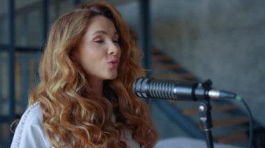 Kadın mikrofonda karaoke yapıyor. Çekici vokalist şarkı söylemeyi öğreniyor.