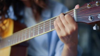 Gitarda akor çalan bir kadın. Gitarda tıngırdayan kız parmakları