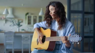 Odada gitar çalan bir kız. İp enstrümanında müzik alıştırması yapan müzisyen