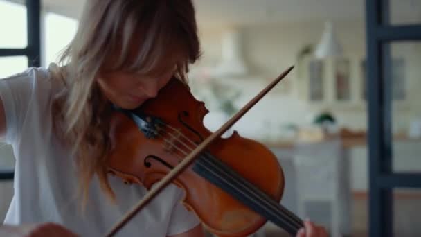 Женщина играет на скрипке в комнате. Девочка-подросток создаёт музыку на струнном инструменте — стоковое видео