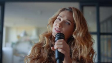 Şarkıcı mikrofonla vokal çalışıyor. Çekici kadın kameraya şarkı söylüyor.