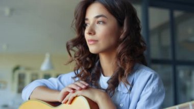 Gitarlı kız oturma odasında rüya görüyor. Akustik gitar tutan romantik bir kadın.