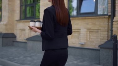 Sokakta aceleyle iş yapan bilinmeyen insanlar. İş kadını kahveyle işe gidiyor.