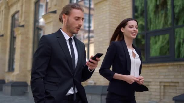 People discussing business. Man using mobile phone on way to work with colleague — Stock Video