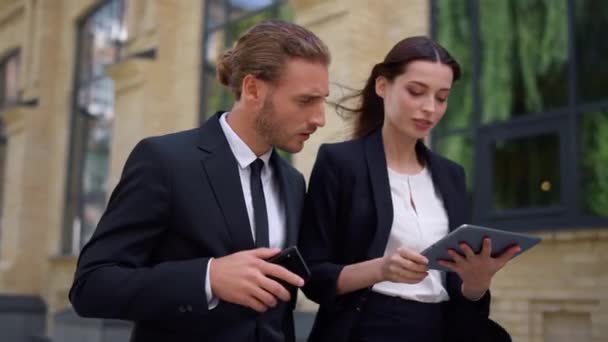 Man en vrouw op zoek naar digitale tablet scherm. Collega 's die met apparaten werken — Stockvideo