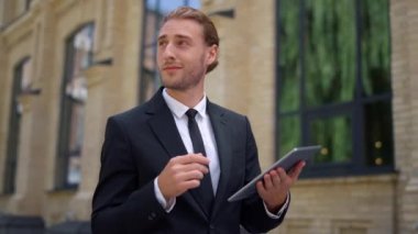 Patron işe yürürken dijital tablet kullanıyor. Takım elbiseli adam el sallıyor..