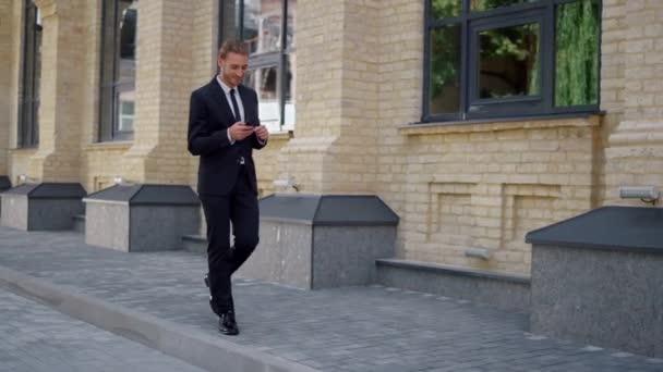 Empresario usando teléfono móvil en la calle. Hombre mirando la pantalla del teléfono celular al aire libre. — Vídeos de Stock