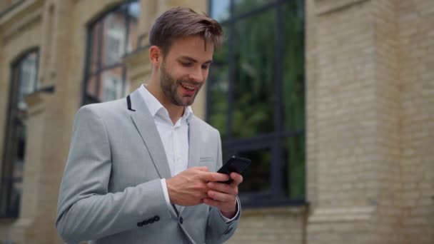 Uomo d'affari che naviga in internet all'aperto. Messaggistica uomo tramite telefono cellulare sulla strada. — Video Stock