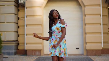 Gülümseyen afro kız şehirde elbise içinde bachata dansı yapıyor. Latin dansı yapan kadın.