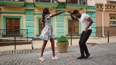 African couple dancing jive in city. Sexy afro dancers making footwork on street clipart