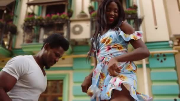 Улыбающаяся афро-леди делает движения на улице. Танцоры, исполняющие латиноамериканские танцы — стоковое видео