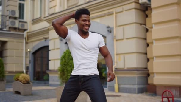 Bailarín africano sonriente moviendo caderas al aire libre. Hombre bailando bachata en la calle — Vídeos de Stock