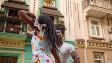 Dışarıda ritmi takip eden pozitif afro çift. Kız ve erkek şehirde dönüyor.