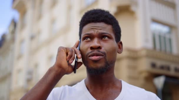 Homem ansioso falando móvel na cidade. afro cara ter telefone conversa no rua — Vídeo de Stock