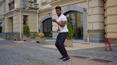 Sokakta Latin dansı yapan Afro adam. Erkek dansçı şehirde vücut hareketleri yapıyor.