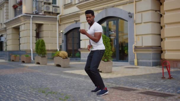 Афро-парень танцует латиноамериканский танец на улице. Мужской танцор, делающий движения тела в городе — стоковое видео