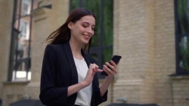Takım elbiseli kadın dışarıda cep telefonu kullanıyor. İş kadını sokakta akıllı telefonla çalışıyor.
