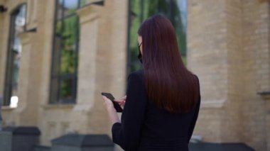Maskeli kadın şehir merkezinde cep telefonu kullanıyor. İş kadını e-posta telefonunu kontrol ediyor