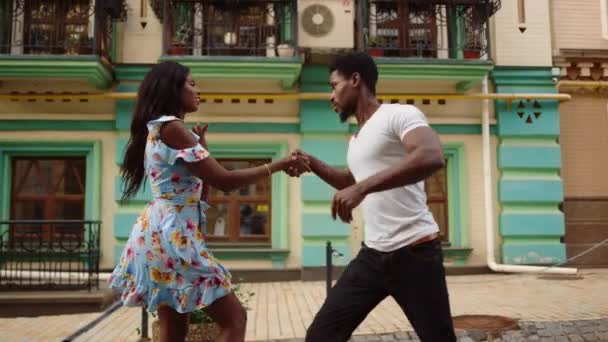 Un afro serio controlando a una chica en el baile de la ciudad. Pareja bailando al aire libre — Vídeos de Stock