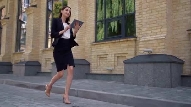 Businesswoman walking to work. Suit lady using digital tablet on city street. — Stock Video
