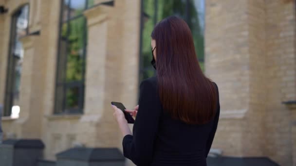 Gemaskerde dame met een mobiele telefoon in het centrum. Zakenvrouw controleren van e-mail telefoon — Stockvideo