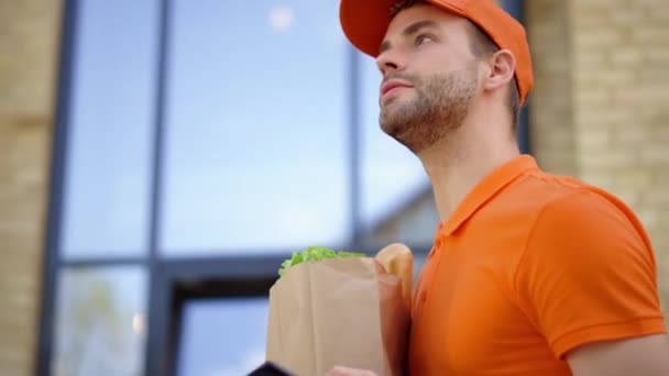 Courier going with paper bag and mobile phone outdoors. Man delivering food. — Stock Video