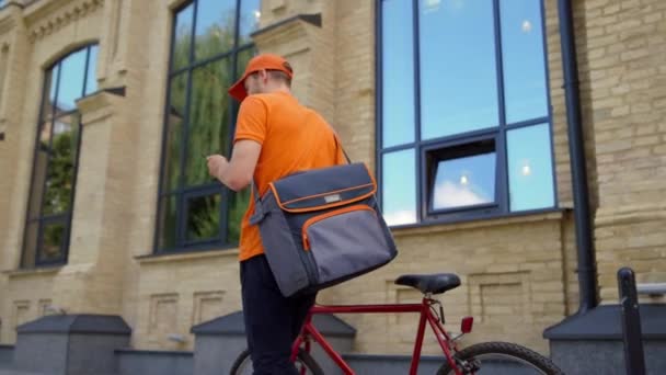 带着手机走近自行车的快递员。派递员在户外用手机 — 图库视频影像