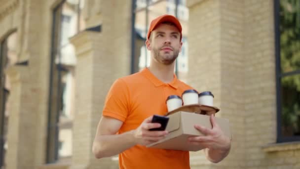 Correio chamando telefone celular ao ar livre. Uniforme cara entregando alimentos e bebidas quentes — Vídeo de Stock