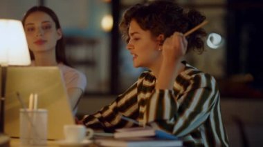 İş kadını ofiste iş arkadaşı konuşuyor. Kalem dizüstü bilgisayarı gösteren kadın