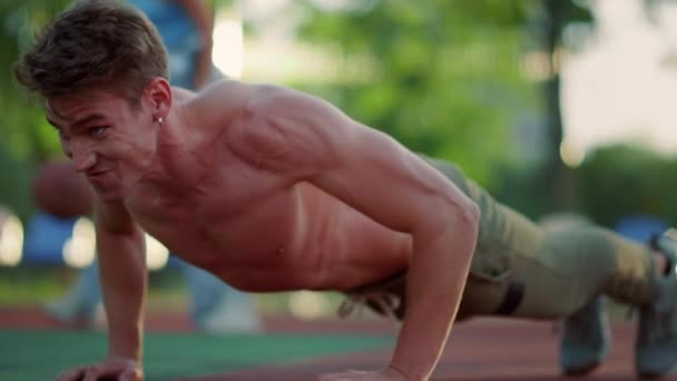 Närbild känslomässig muskulös idrottsman gör armhävningar i sport lekplats utomhus. — Stockvideo
