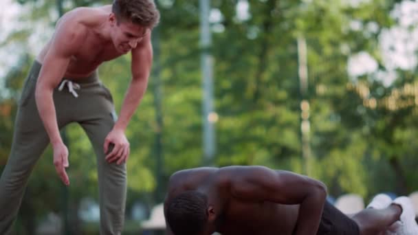 Тренер фітнесу тренує афроамериканського чоловіка на ігровому майданчику.. — стокове відео
