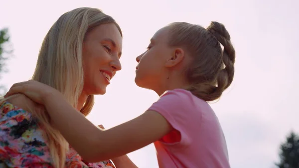 Mignonne mère et fille qui se regardent dans le parc de la ville au coucher du soleil. — Photo