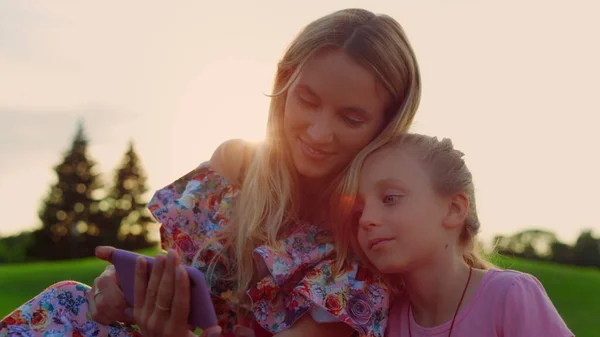 Mulher e menina olhando para o telefone móvel no parque. Família passar fim de semana ao ar livre. — Fotografia de Stock