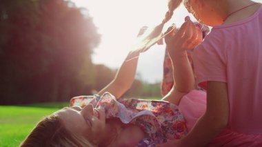 Neşeli kadın güneşli bir günde şehir parkında güzel bir kızla vakit geçiriyor..