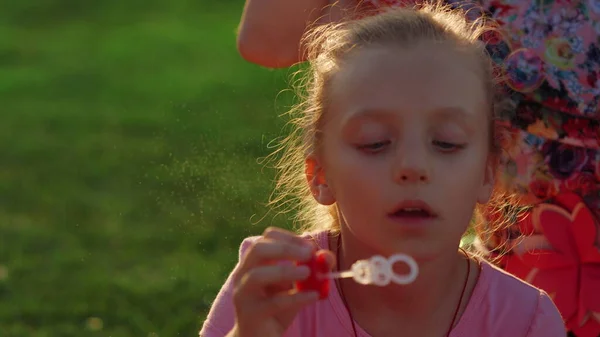 Jolie fille se détendre dans le jardin. Femme enfant soufflant des bulles de savon dans le parc de la ville. — Photo