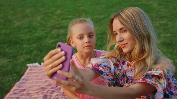 Madre e hija posando en el parque. Familia tomando selfie en el teléfono celular al aire libre. — Foto de Stock