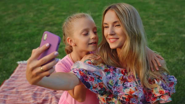 Chica besándose mujer en el jardín. Familia tomando selfie en el teléfono móvil al aire libre. — Foto de Stock
