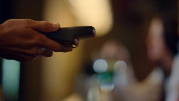 Bezoeker hand betalen met mobiele telefoon binnen. Hand geven terminal voor de betaling. — Stockvideo