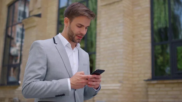 Homem usando telefone celular em movimento ao ar livre. Gerente olhando celular na rua. — Fotografia de Stock