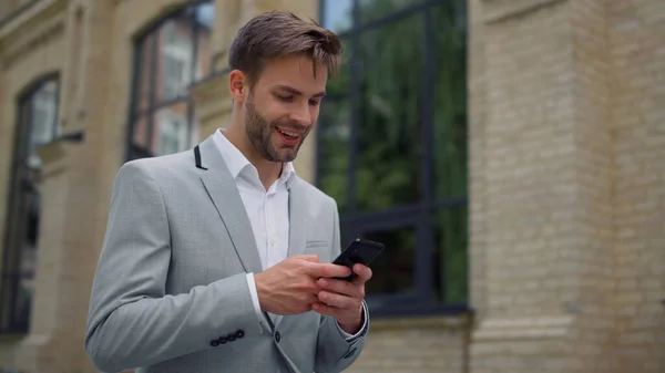 Empresário surfando na internet ao ar livre. Mensagens de homem por telefone celular na rua. — Fotografia de Stock