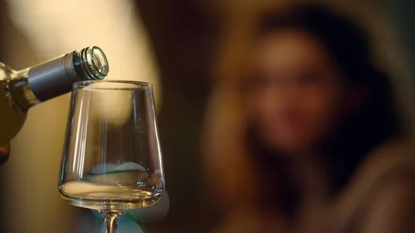 Άγνωστος μπάρμαν ρίχνει κρασί από μπουκάλι. Θολή γυναίκα που παίρνει γυαλί σε εσωτερικούς χώρους. — Φωτογραφία Αρχείου