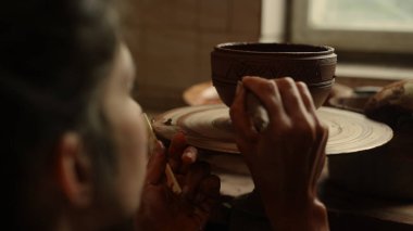 Bilinmeyen kadın çanak çömlek aletleri kullanıyor. Sanatçı kil çömleğe süs çiziyor 