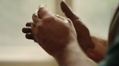 Tanınmayan seramikçi çömlek içinde kil hazırlıyor. İnsan elleri kilden heykel yapıyor.