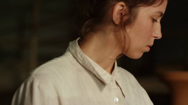 Hayalperest kız çömlekçilik hakkında bir şeyler düşünüyor. Stüdyoda yürüyen kadın