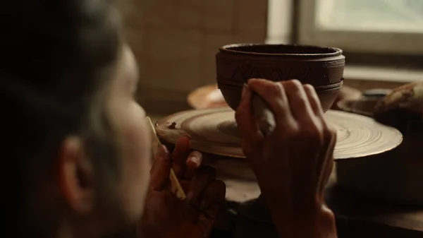 Neznámá žena používající nářadí v keramice. Umělec kreslení ornament na hliněný hrnec — Stock fotografie
