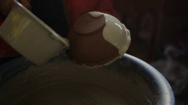 Tanımlanamayan bir kadın atölyede ürünlere boya döküyor. Sanatçı esrar boyuyor