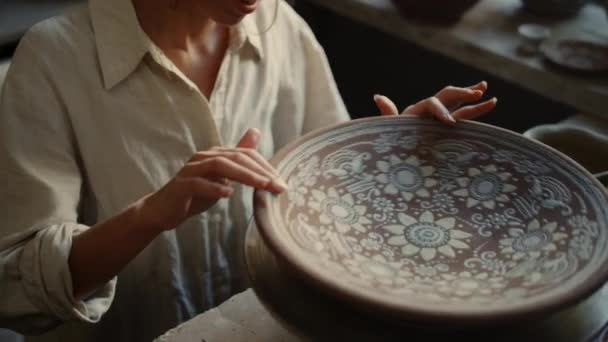 Lächelnder Keramiker berührt Tonteller in Werkstatt. Mädchen schaut auf Tonprodukt — Stockvideo