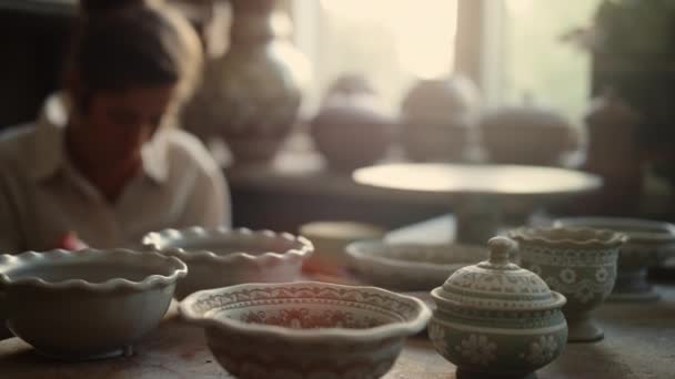Focused artist making picture on pot in pottery. Woman decorating clay product — Stock Video